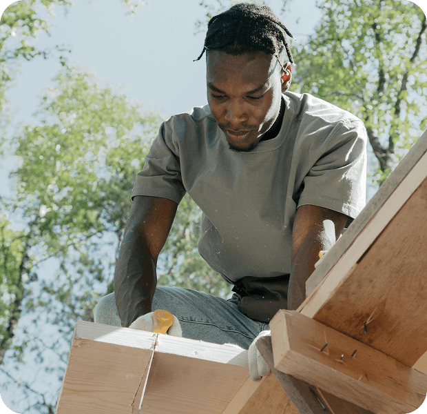 Skilled worker outdoors with lumber and tools, completing a hands-on project
